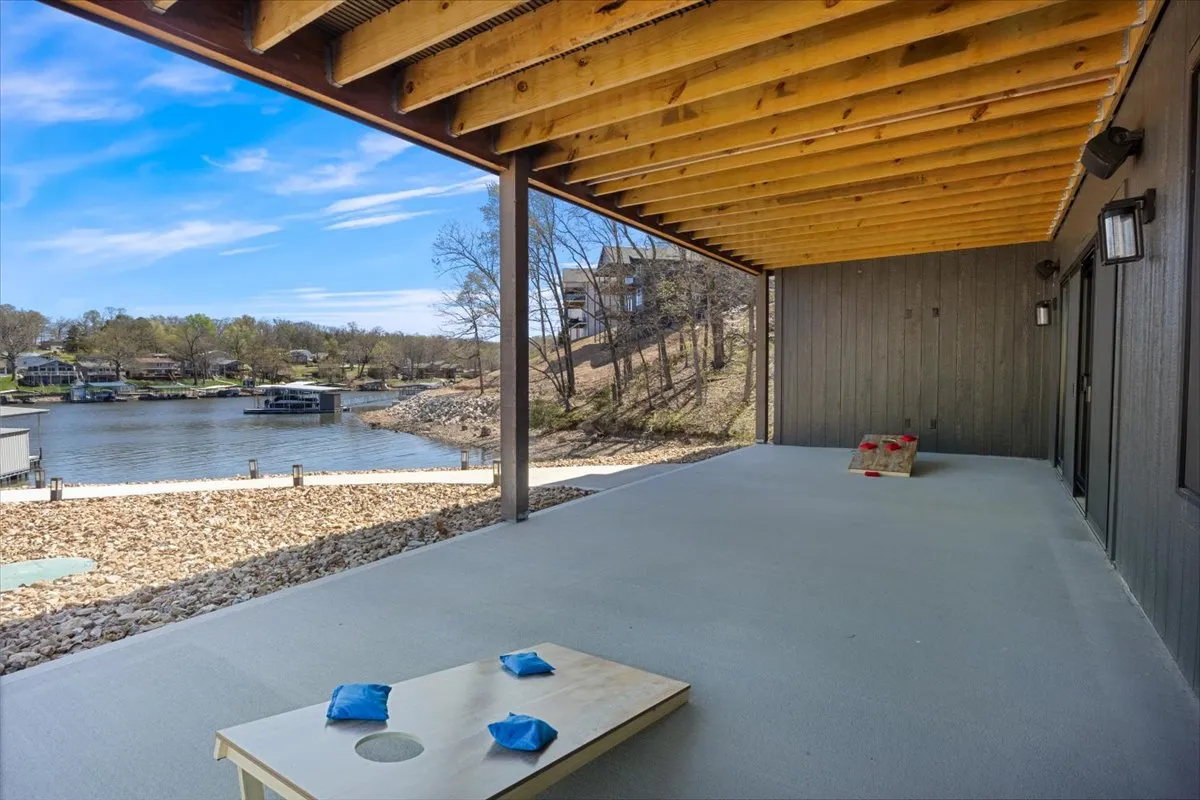 A patio area overlooking the lake invites guests to play cornhole, relax by the water, or gather for social activities. The setup highlights both leisure and accessibility, with an open, level surface ideal for guests of all ages and abilities to participate in outdoor fun.