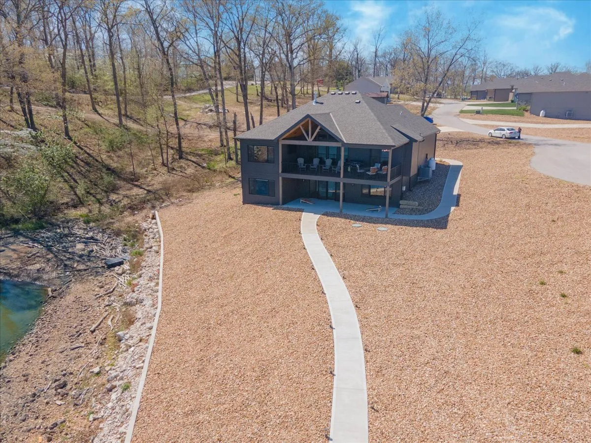 This exterior image showcases the house nestled in a tranquil landscape, with a welcoming pathway leading up to the porch and natural surroundings all around. The peaceful setting hints at privacy and serenity, embodying a sense of retreat. The porch is visible, suggesting a comfortable spot to unwind and take in nature.