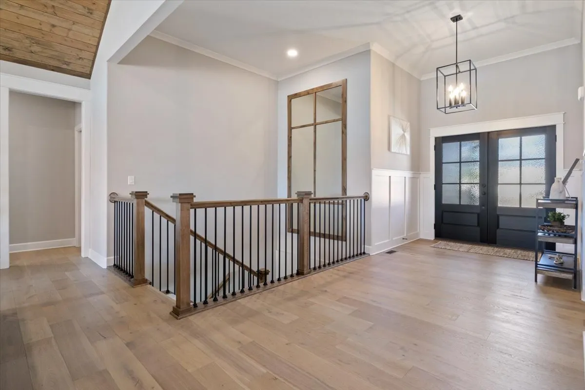 This interior image presents the entryway with a sturdy staircase and welcoming front doors. The well-lit, orderly area features thoughtful decor, including a mirror and shelf, which creates a sense of invitation and order for arriving guests.