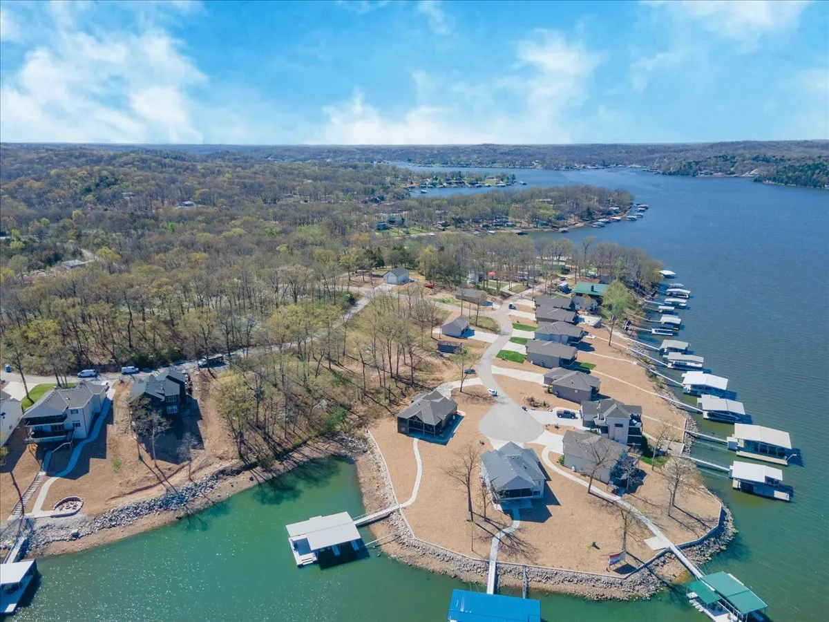 The photo shows a serene lake with private docks extending into the water, surrounded by trees and neighboring houses. It conveys opportunities for boating, fishing, and lakeside relaxation, with the dock easily visible and accessible for all guests.